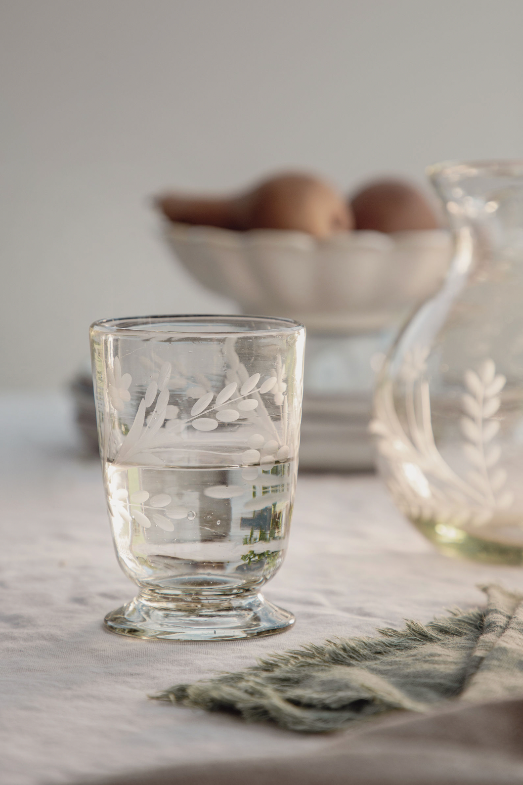 Delicate stenciled crystal glass with glass jug in background
