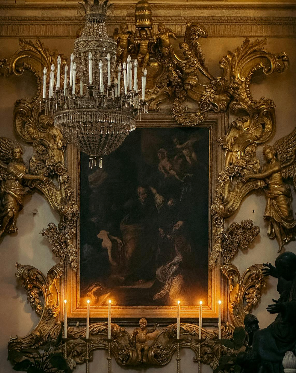 Opulent gold mirroe surrounded by chandelier and sconces with real candles
