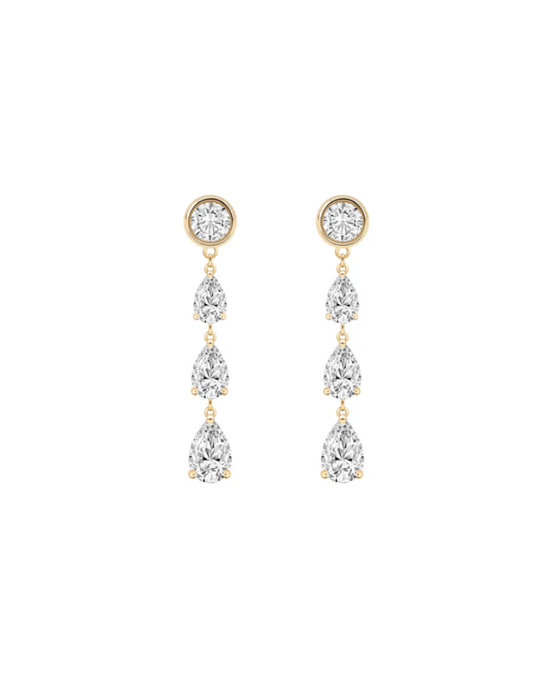 a pair of silver and gold earrings with three hanging diamonds each.