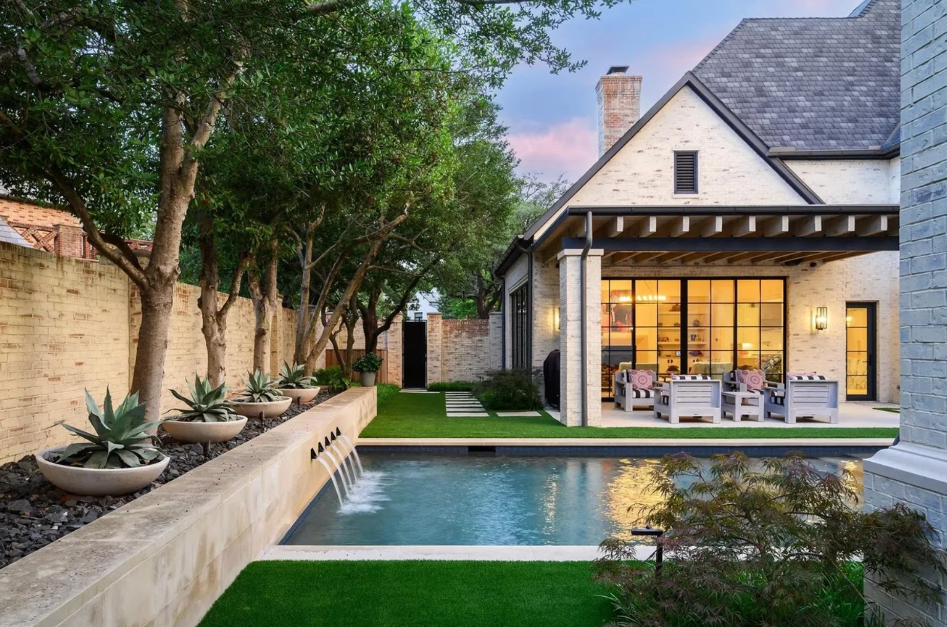 Outside of house with big pool and outdoor furniture in background.