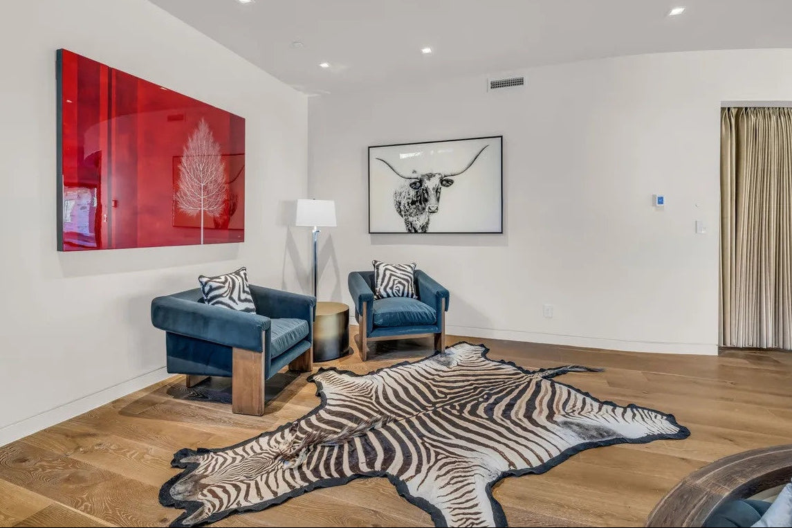 A room shot if zebra rug and two blue sofa couches with zebra pillows.