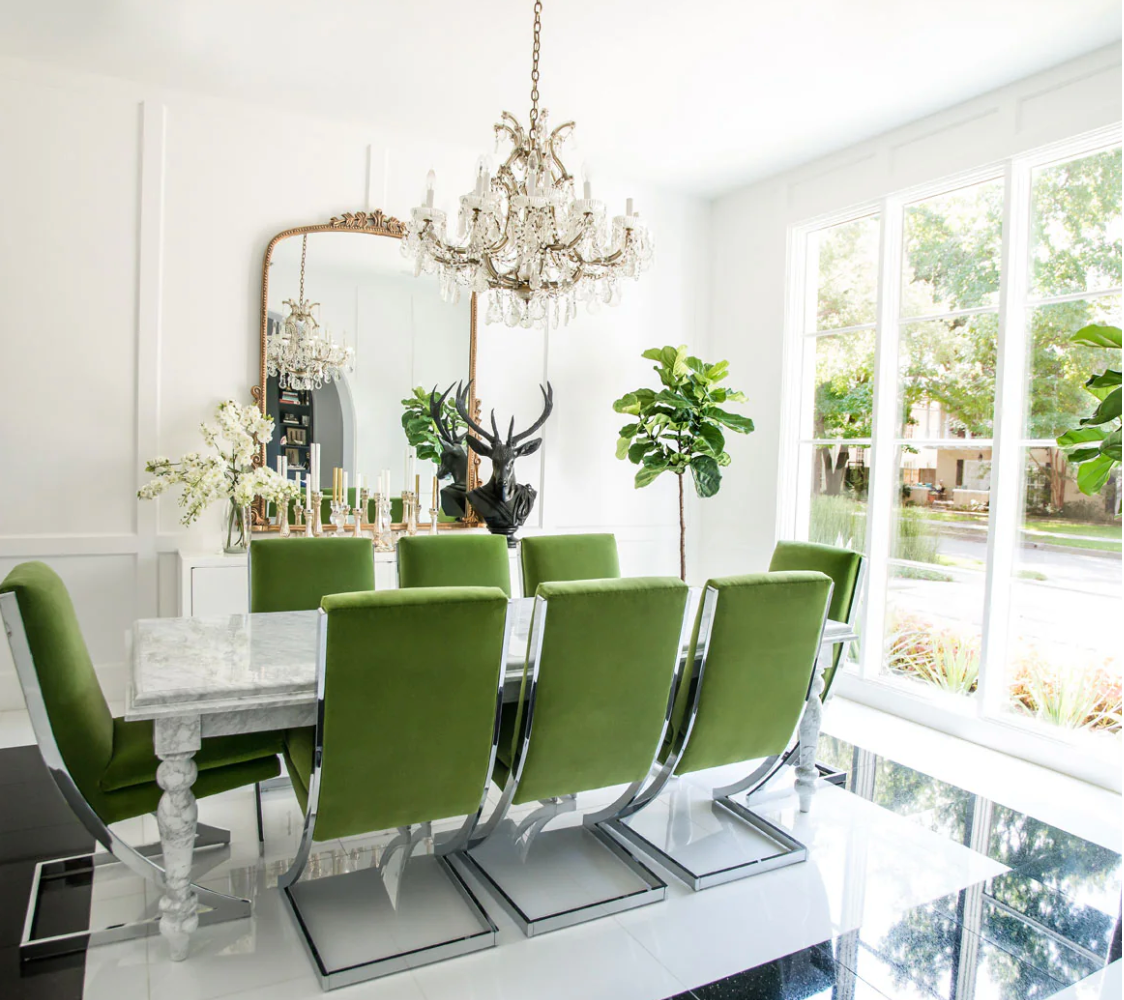 Modern dining room with green chairs, a chandelier, and large windows.