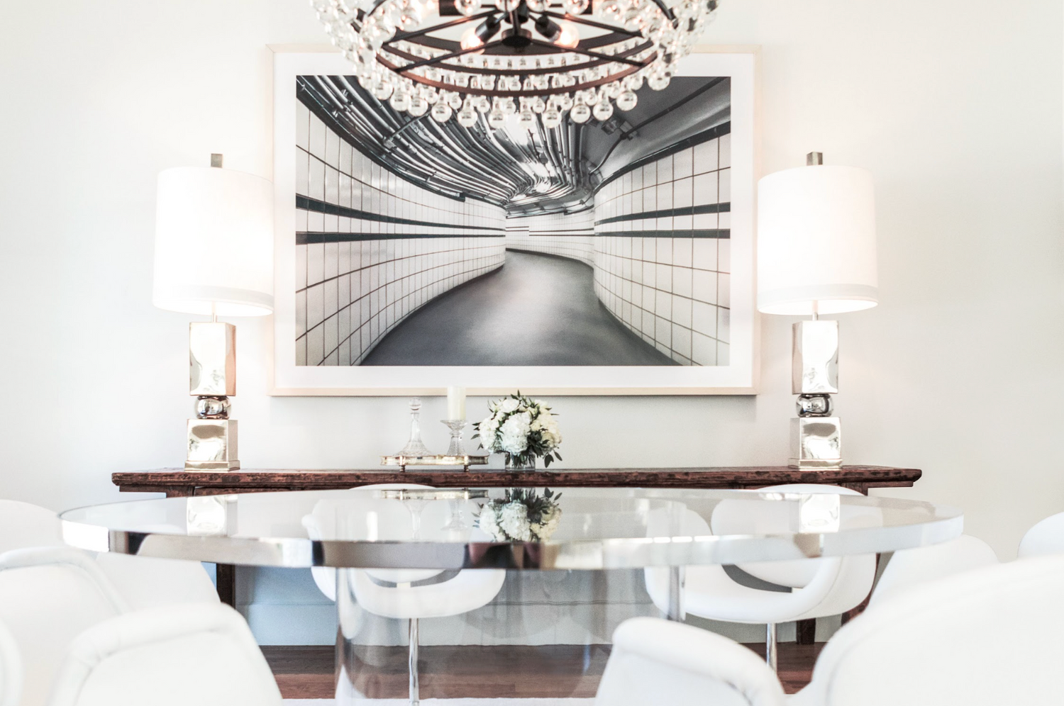 console table behind the dinning room displays wall art, lamps and florals