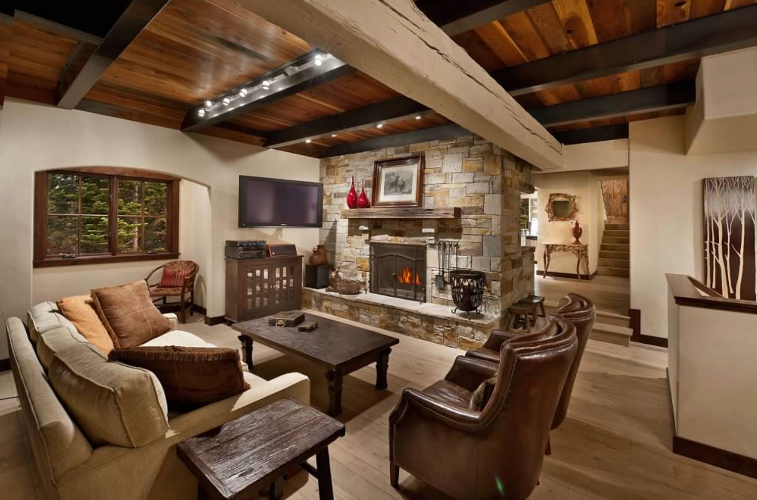 Cozy living room with stone fireplace, wooden beams, and comfortable furniture.