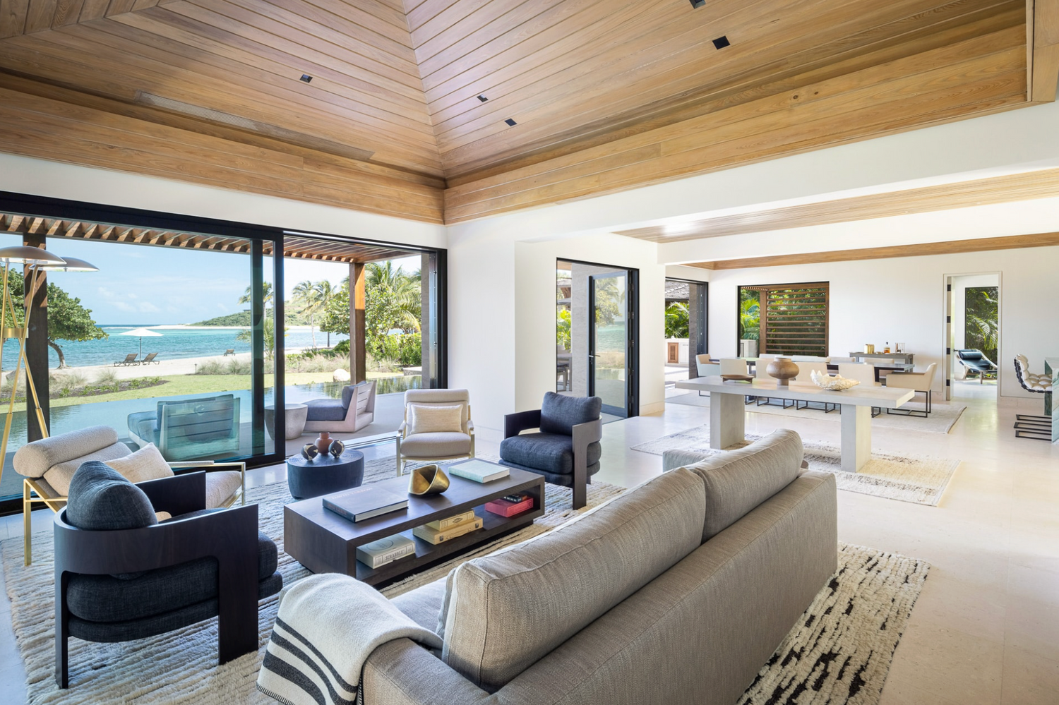 Modern living room with large windows overlooking a beach.