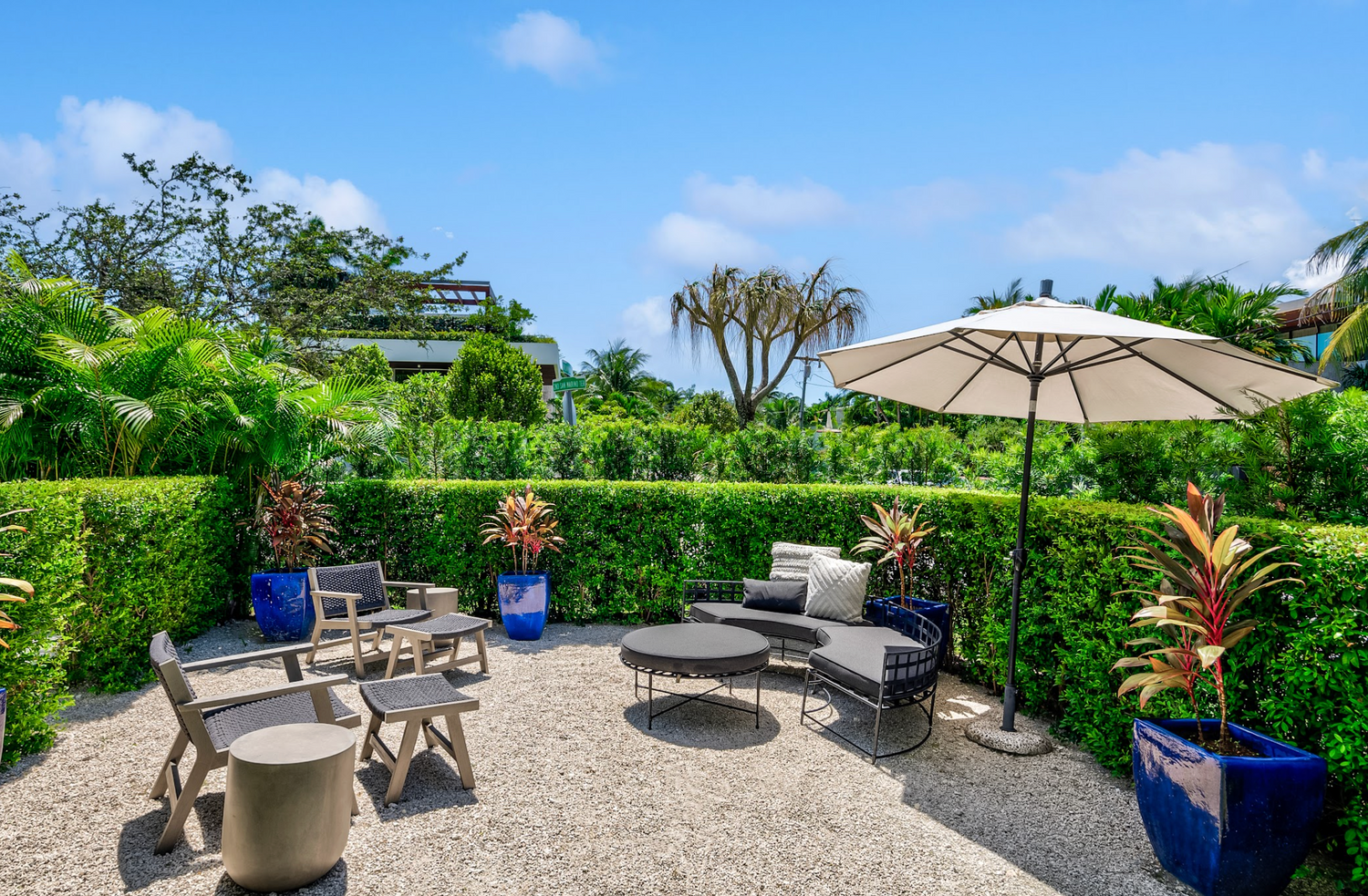 Wide angle shot of the patio with a hedge and seating and umbrellas
