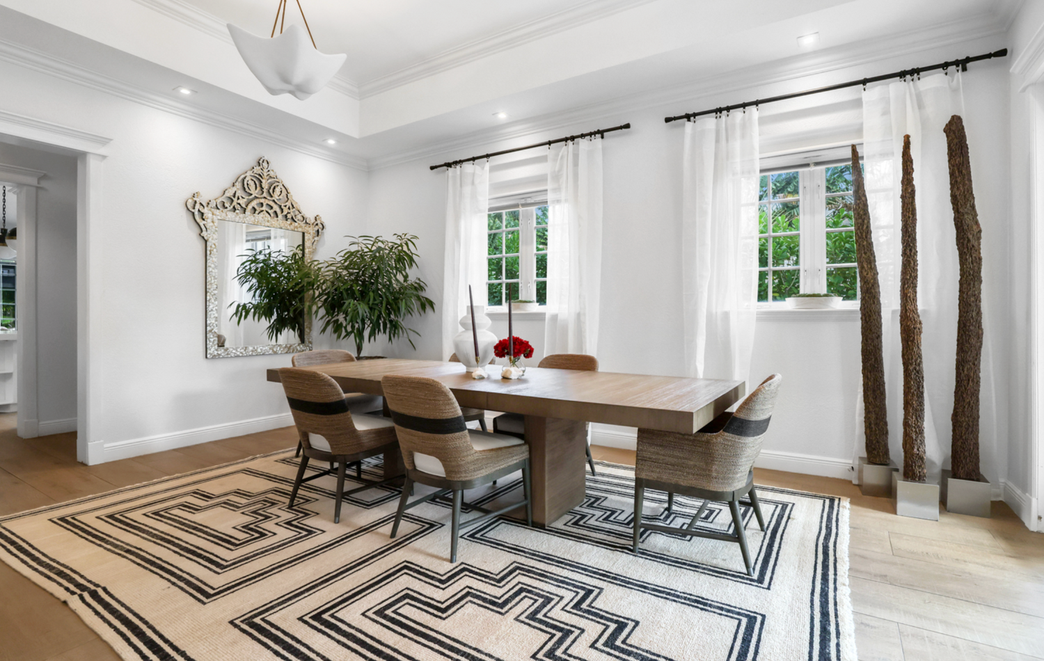 Modern dining room with a wooden table and chairs on a patterned rug.