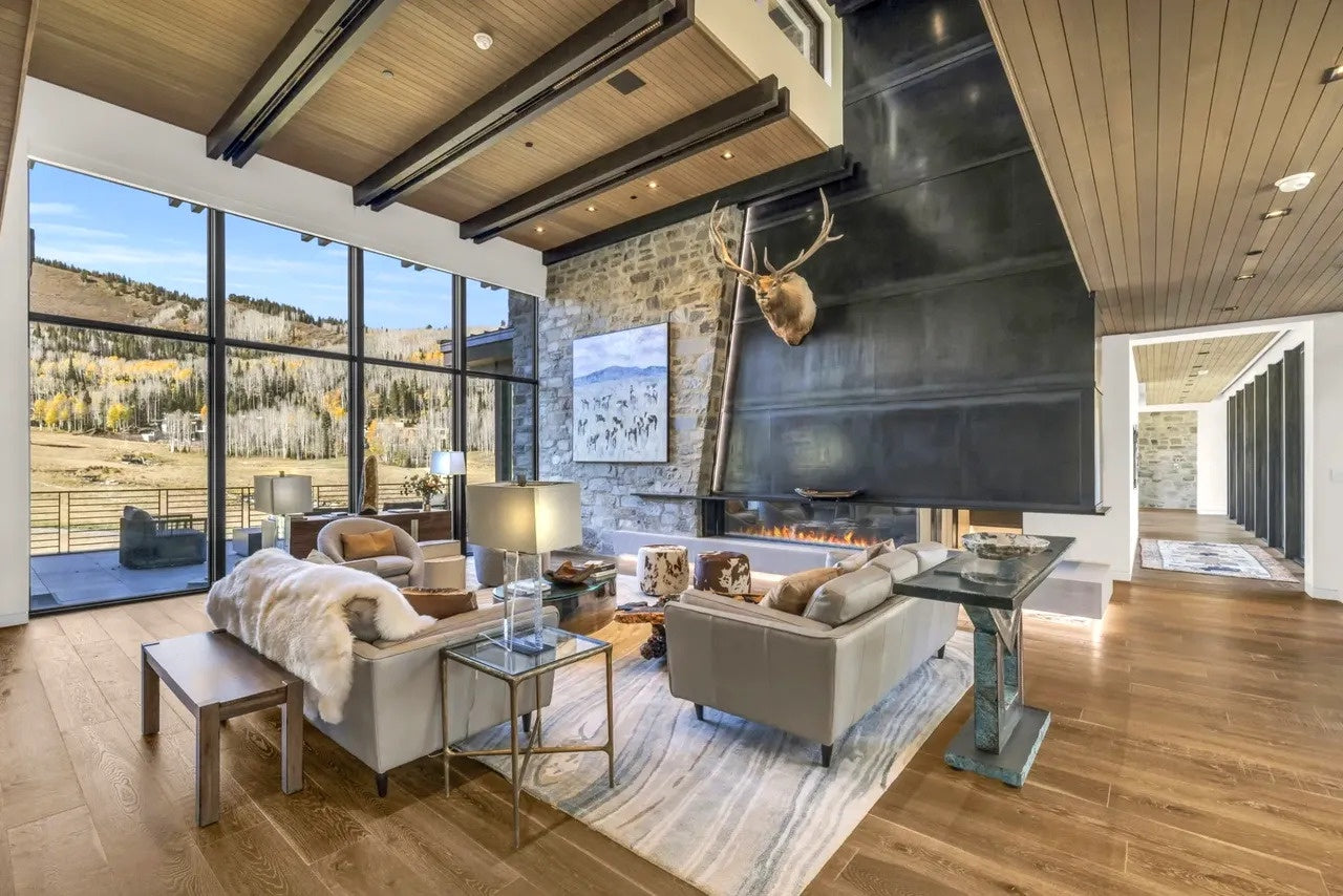 Modern living room with large windows, fireplace, and mountain view.